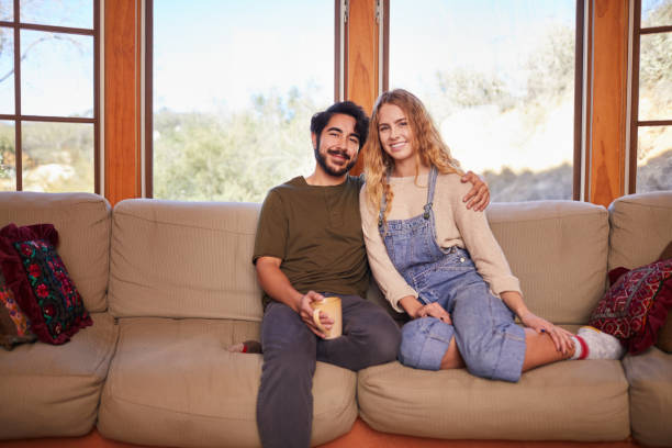 istock Young couple smiling while sitting together on a sofa 1181846348