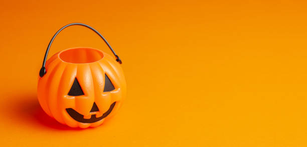 istock Halloween. Pumpkin candy basket on an orange background. 1181849630