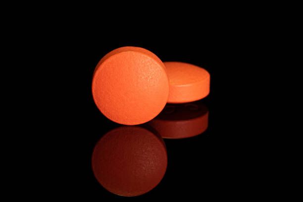 istock Orange pharmacy tablet isolated on black glass 1181850274