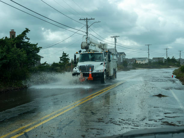 Utility truck navigates flood damaged road Falmouth, Massachusetts - Oct 18, 2019: A utility truck drives along flood and storm damaged Surf Drive during a bomb cyclone storm. truck rain stock pictures, royalty-free photos & images
