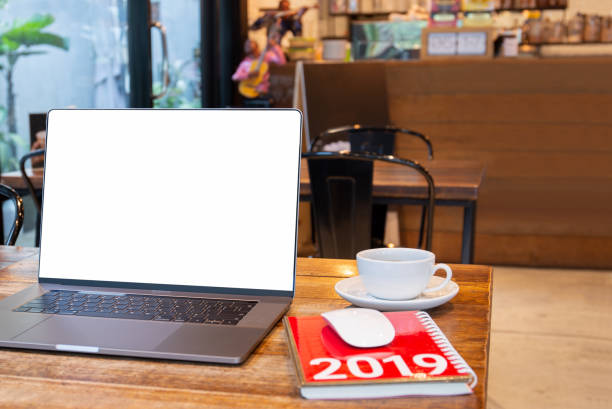 istock Blank screen laptop with mouse and coffee cup and notebook with Year 2019 calculator on table in cafe. 1181853382