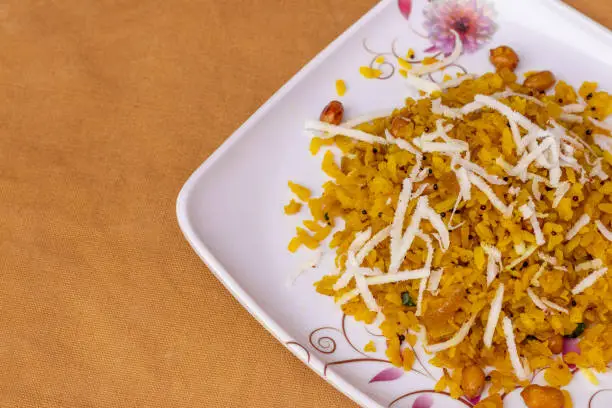 Photo of Poha popular healthy Indian breakfast dish made with flattened rice served in plate.