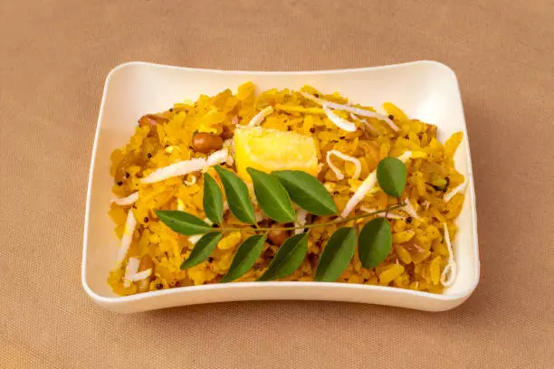 Photo of Poha popular healthy Indian breakfast dish made with flattened rice served in plate.