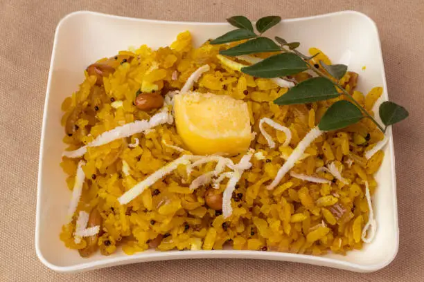 Photo of Poha popular healthy Indian breakfast dish made with flattened rice served in plate.