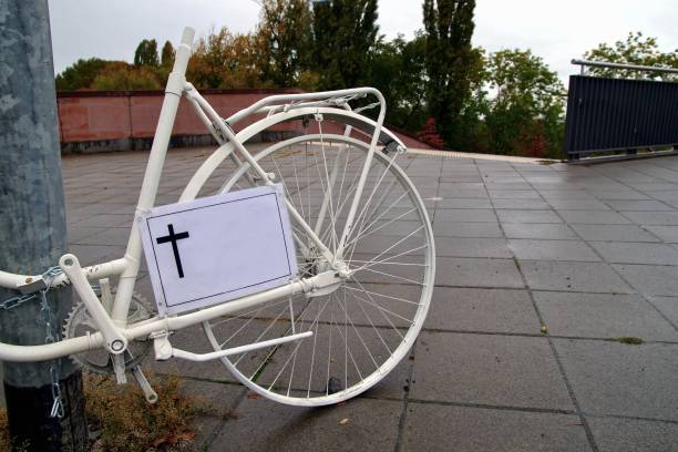 雨の日にドイツのフランクフルト・マインで死亡したサイクリストのためのクロスサインを持つゴーストバイクの記念碑。白い幽霊自転車、交通事故で死亡したサイクリストへの追悼 - memorial roadside cross cross shape ストックフォトと画像