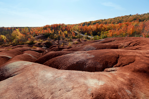 Amazingly beautiful red clay hills near Caledon, Ontario, Canada, called Cheltenham Badlands - badlands formation (exposed and eroded Queenston Shale) on a sunny day in October with fall colored trees. Travelling in Ontario. Ontario day trip ideas. Red soil looking like in an outer world. Mars like soil in Ontario. Canadian must see places. Beautiful vista