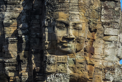 The ruins of the religious temple complex of Angkor Wat, Cambodia. A face carved in stone.