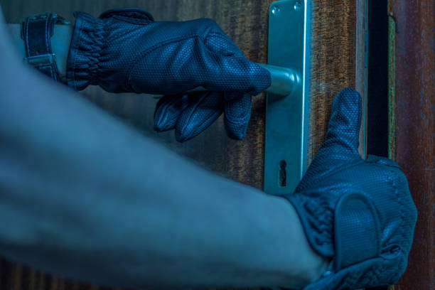 istock burglar carefully opens a flat door with his hands inside the flat 1181872631