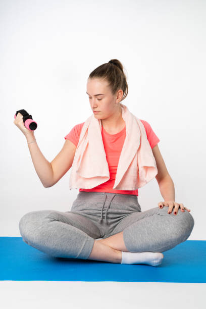 istock A young woman does a barbell exercise on a yoga mat 1181873793