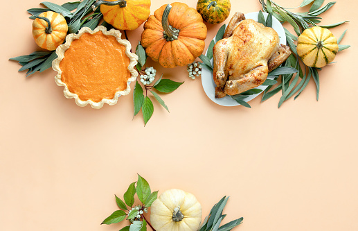 Thanksgiving dinner invitation concept or mock up, top down view on autumn traditional food decorated with pumpkins and sage