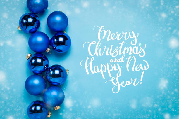 istock Blue Christmas tree toys, balls on a blue background with falling snow. Added text Merry Christmas and Happy New Year. Flat lay, top view 1181886504