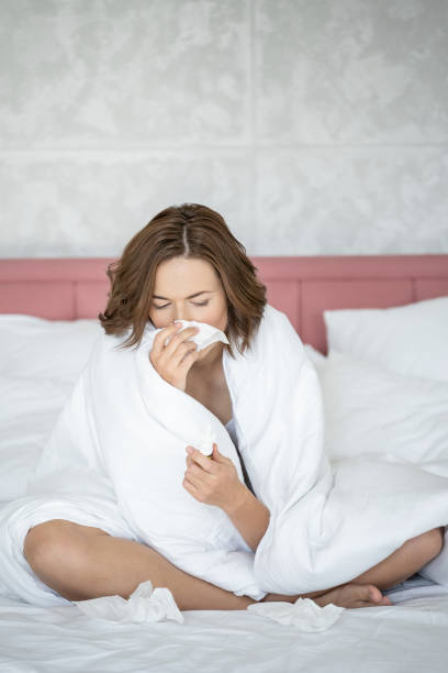 istock Ill woman blowing her nose in bed 1181891739