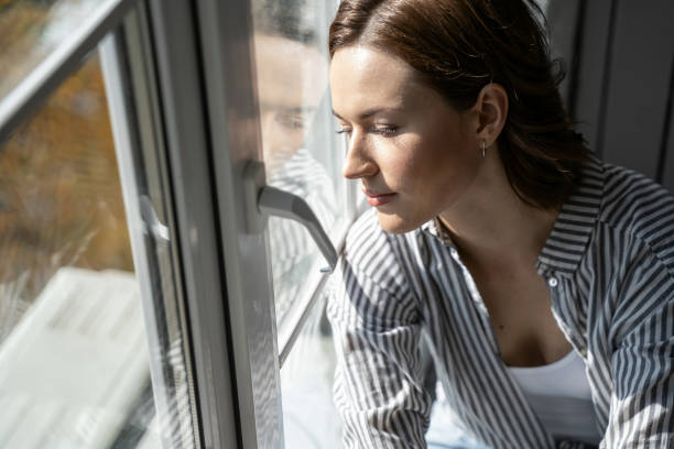 istock Relaxed young female looking through the window 1181891768