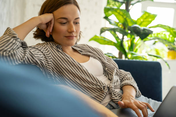 istock Female sitting with a laptop on the sofa 1181891848