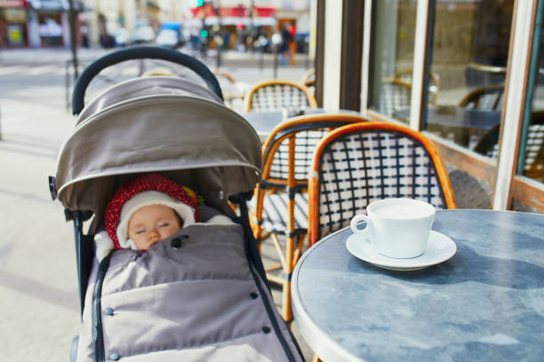 Baby girl sleeping in pram on outdoor terrace of Parisian street cafe stock photo