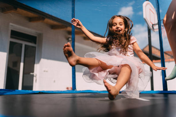 Girls jumping on trampoline Girl wearing princess costume jumping on trampoline with a older girlfriend trampoline stock pictures, royalty-free photos & images