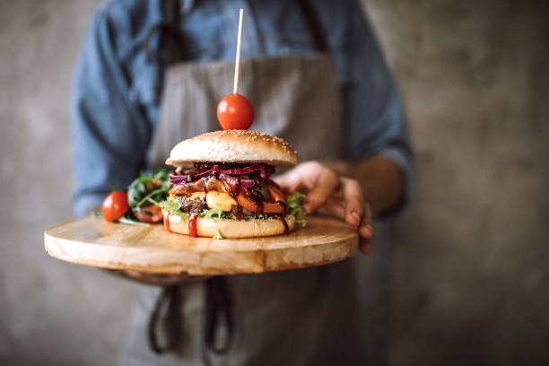 istock Proud chef with served cheeseburger on wooden plate 1181904830
