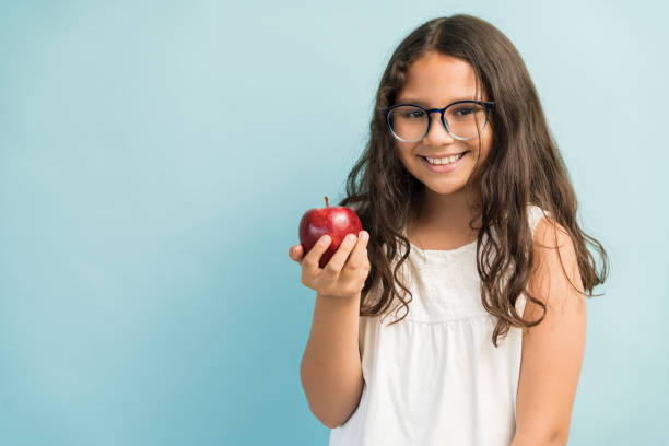 istock Cute Girl With Healthy Fruit Standing Against Plain Background 1181905818