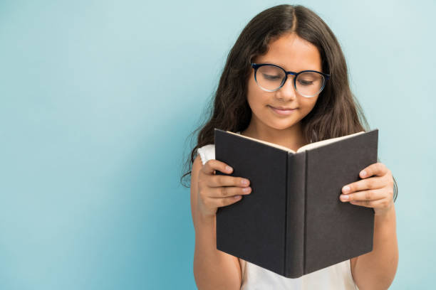 menina bonito que estuda de encontro ao fundo liso - reading girl - fotografias e filmes do acervo