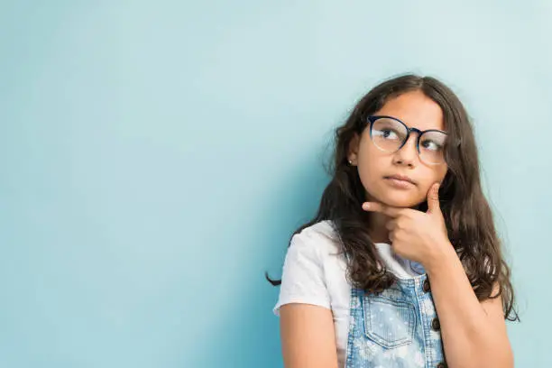 Photo of Hispanic Girl Day Dreaming Against Plain Background