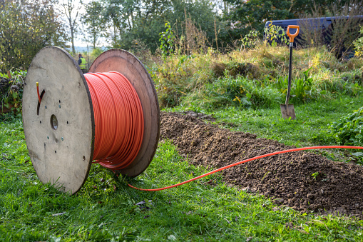Bobina de madera con cable de fibra óptica para Internet rápido listo para ser colocado en estrechas trincheras en el suelo en un prado, expansión de la infraestructura en el campo photo