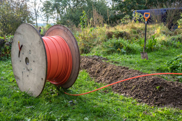 bobina de madera con cable de fibra óptica para internet rápido listo para ser colocado en estrechas trincheras en el suelo en un prado, expansión de la infraestructura en el campo - fibra fotografías e imágenes de stock