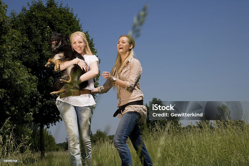 Dwóch młodych kobiet gra na zewnątrz z psem - Zbiór zdjęć royalty-free (Adolescencja)