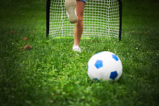 Happy Brazilian family outdoors playing football - focus on the goal