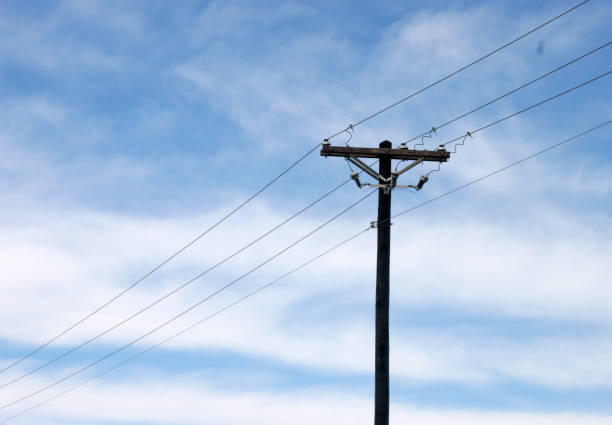 istock Utility Pole and Lines Against Blue Sky with Clouds 1181909398