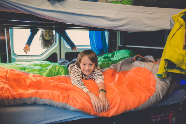 Children, having fun in camper van while heavy raining outdoors, playing and making mischiefs