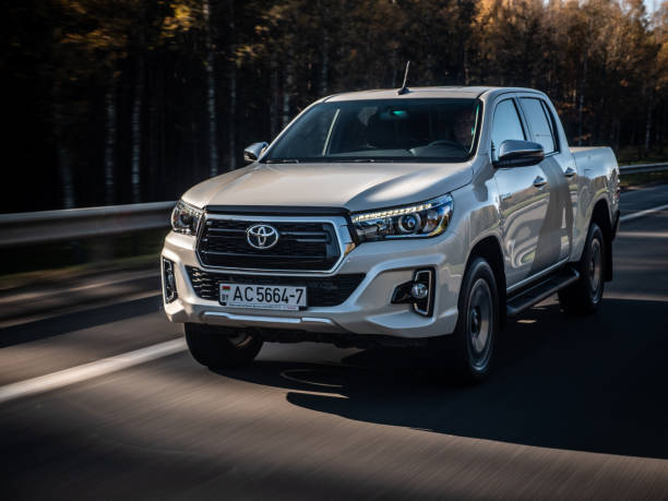 Toyota Hilux Exclusive Minsk, Belarus - October 17, 2019: Pearl white Toyota Hilux 2.8 D-4D Exclusive drives on a highway during bright sunny day. toyota hilux stock pictures, royalty-free photos & images