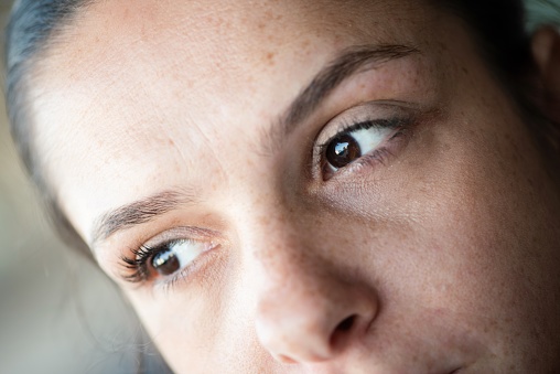 Extreme closeup of a freckled woman looking away.