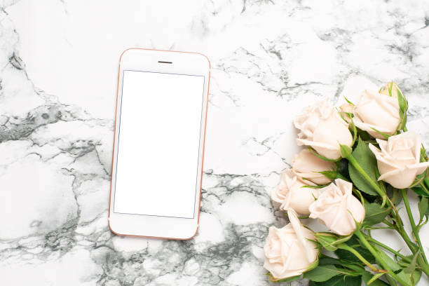 istock Mobile phone with roses flowers on a marble background 1181916572
