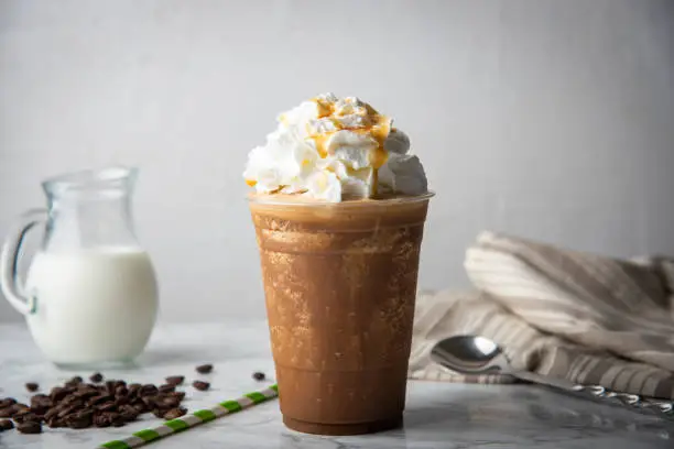 Photo of caramel frappuccino with wipped cream on marble table