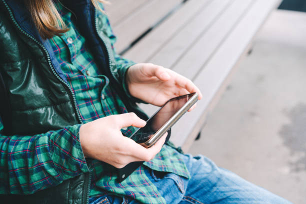istock A boy is sitting on the bus stop bench with a broken phone in his hands 1181926888