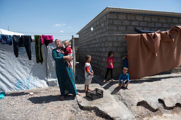 Syrian-Kurdish refugees living in Iraq A Syrian-Kurdish woman and several children stand outside a home in Darashakran refugee camp in Iraqi Kurdistan (May 2017) iraqi kurdistan stock pictures, royalty-free photos & images