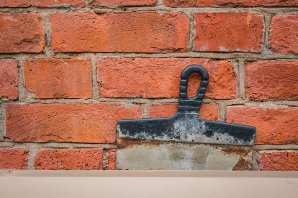 istock Old spatula on a brick wall. Repair completion concept. 1181928156