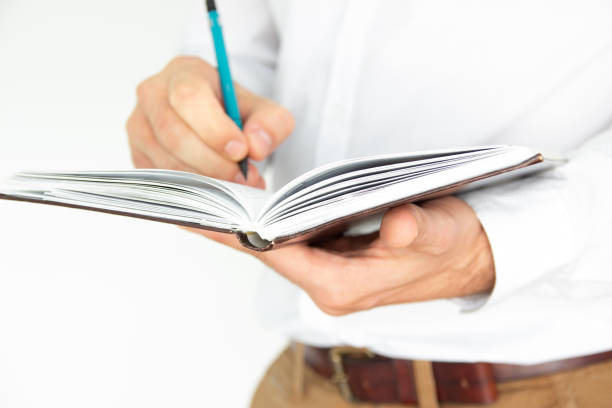 istock A man holds in his hands a notebook, notebook, diary and pen. Business concept isolated on white background. 1181929427