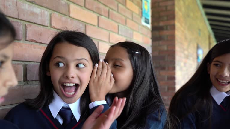 Latin American girls at school telling secrets and looking very happy