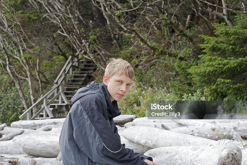 Adolescente sentado en Driftwood - Foto de stock de 14-15 años libre de derechos