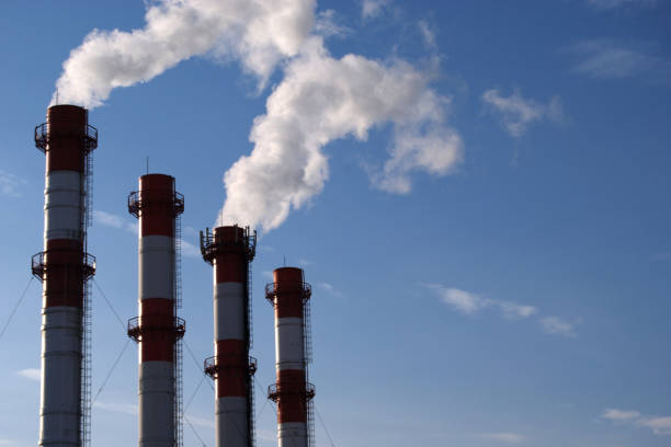 istock Four smoking factory chimneys in blue sky 1181935566