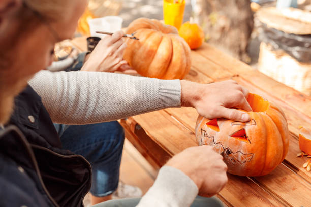 młody dorosły mężczyzna i kobieta robiący dynię jack-o-lantern - two jack zdjęcia i obrazy z banku zdjęć