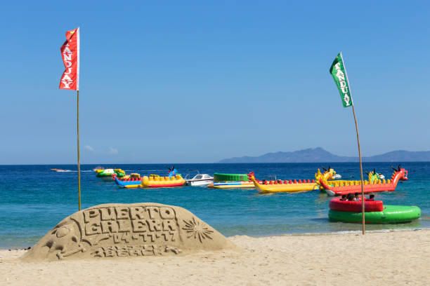 Puerto Galera - April 4, 2017: Sand castle with sign "Puerto Galera" on White beach with tourists and water activities on background Puerto Galera - April 4, 2017: Sand castle with sign "Puerto Galera" on White beach with tourists and water activities on background sabang beach stock pictures, royalty-free photos & images