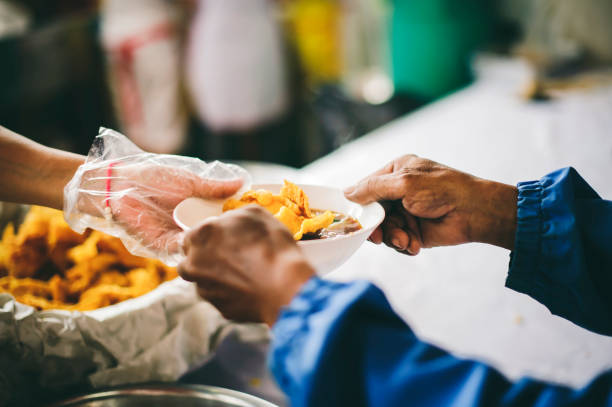 voluntários que escoam a comida para compartilhar com os necessitados: conceito de fornecer comida gratuita para pessoas sem-teto. - esfomeado - fotografias e filmes do acervo