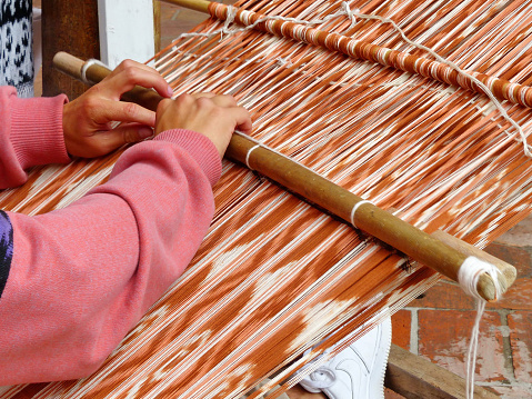 Close up of traditional weaving technique Ikat for making scarfs or Macana or other fabric by hand with cotton threads, design are traditional for Gualaceo canton, Azuay province, Ecuador