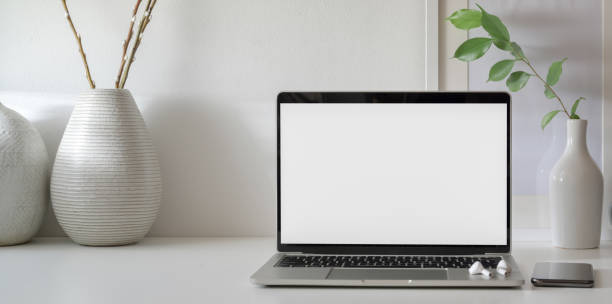 istock Open blank screen laptop computer in minimal workspace with copy space and ceramic vase 1181972048