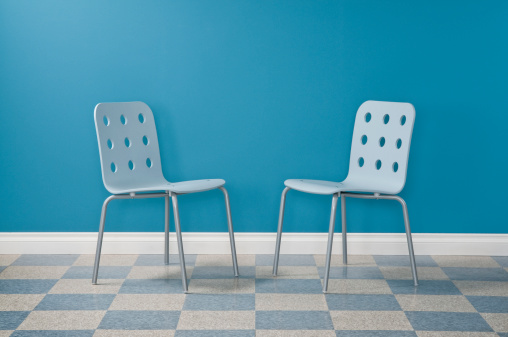 Austere waiting room with two modern chairs.*