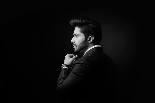 Indian bearded Male businessman showing side profile, standing over black background