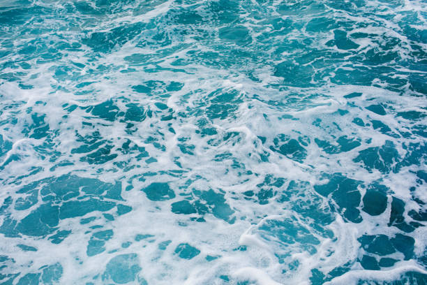 istock Turquoise sea surface background with splashing waves 1181984725