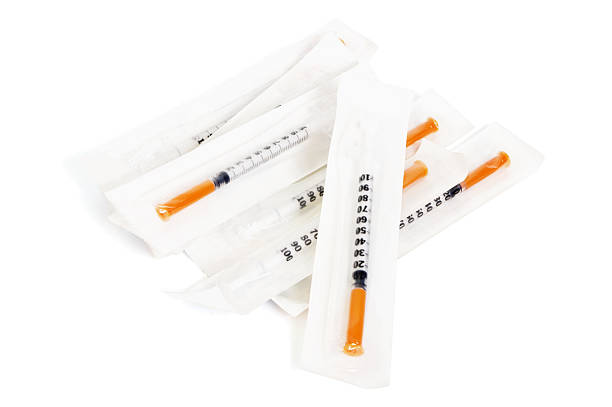 Small 100 units syringes in sealed sterile packets. Isolated on white with some soft shadow.